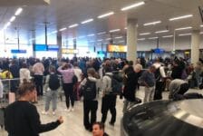 Drukte op Schiphol bij bagageband, honderden mensen bij elkaar